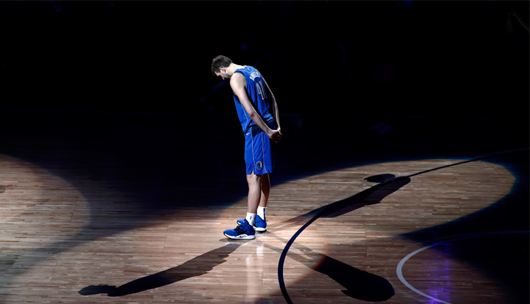 Dirk steht alleine auf dem Feld während er einer Laudatio zuhört